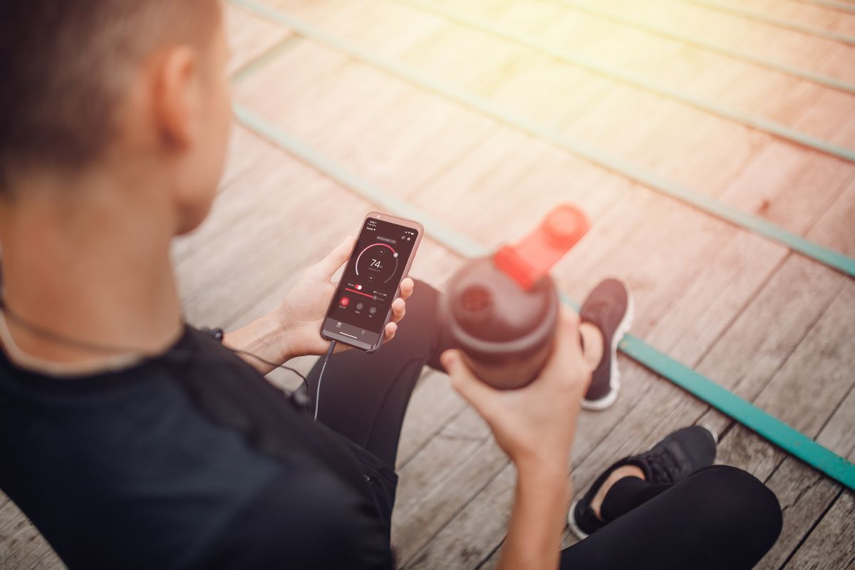atlet, der holder en vandflaske og en telefon