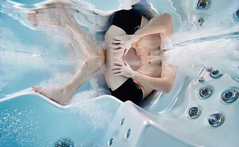 Kvinde slapper af i en ergonomisk liggestol i en USSPA-spapool med hydromassagedyser i drift